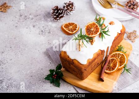 Obstkuchen mit Glasur, Nüssen und trockenem Orange auf Steingrund bestäubt. Weihnachten und Winterferien Stockfoto