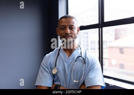 Portrait von lächelnd gemischte Rasse männlichen Arzt trägt Scrubs und Stethoskop Stockfoto