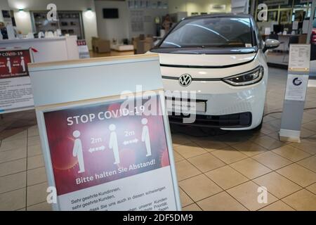 Berlin, Deutschland. Dezember 2020. Ein Schild mit der Aufschrift 'Stop Covid-19' steht vor dem Elektroauto Volkswagen ID.3 in einem Autohaus. Quelle: Jörg Carstensen/dpa/Alamy Live News Stockfoto