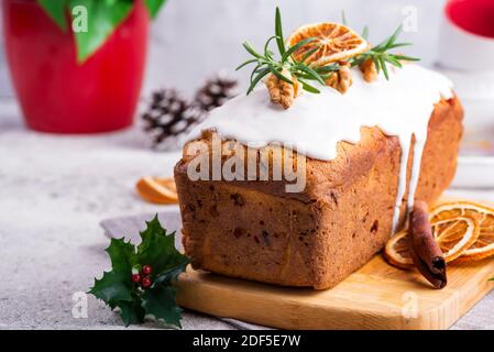 Obstkuchen mit Glasur, Nüssen und trockenem Orange auf Steingrund bestäubt. Weihnachten und Winterferien hausgemachter Kuchen Stockfoto