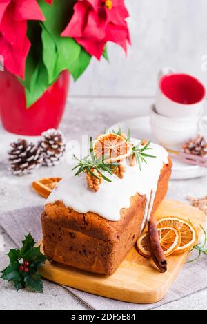 Obstkuchen mit Glasur, Nüssen und trockenem Orange auf Steingrund bestäubt. Weihnachten und Winterferien hausgemachter Kuchen Stockfoto