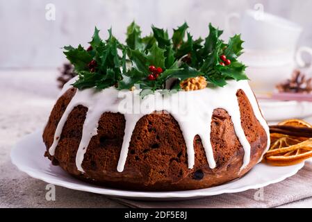 Weihnachten hausgemachte dunkle Schokolade gebündelt Kuchen mit weißer Glasur verziert Und Stechbeerzweige aus der Nähe Stockfoto