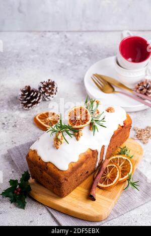 Obstkuchen mit Glasur, Nüssen und trockenem Orange auf Stein Hintergrund bestäubt. Weihnachten und Winterferien hausgemachter Kuchen Stockfoto