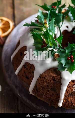 Weihnachten hausgemachte dunkle Schokolade gebündelt Kuchen mit weißer Glasur verziert Und Stechbeerzweige aus der Nähe Stockfoto