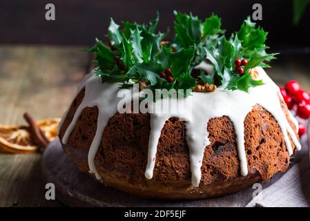 Weihnachten hausgemachte dunkle Schokolade gebündelt Kuchen mit weißer Glasur verziert Und Stechbeerzweige aus der Nähe Stockfoto