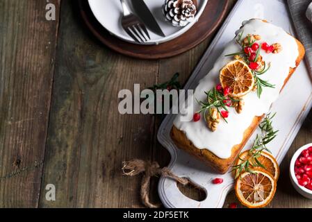 Obstkuchen mit Glasur, Nüssen und trockenem Orange auf altem Holzhintergrund bestäubt. Weihnachten und Winterferien hausgemachter Kuchen Stockfoto