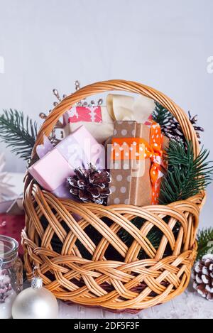 Weihnachtskomposition mit Schachtel, Korb, Tannenzapfen und Dekorationen auf weißem Holz mit Kopierraum Stockfoto