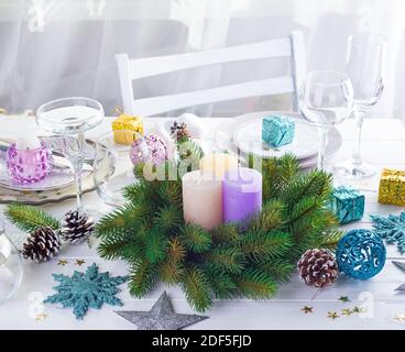 Tischeinstellung für weihnachtlichen weißen Tisch mit violettem Dekor Elemente und grünen Kranz Weihnachtsbaum Stockfoto
