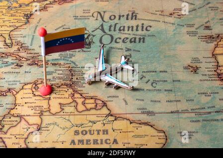 Die Flagge Venezuelas und das Flugzeug auf der Weltkarte. Das Konzept von Reisen und Tourismus. Stockfoto