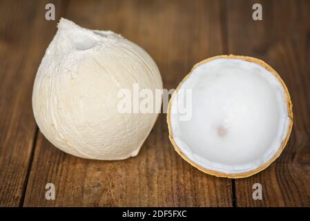 Schneiden Sie halb Kokosnuss und frische Kokosnüsse auf alten Holztisch Für Essen Stockfoto