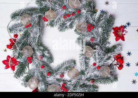 Weihnachtskarte mit Dekor und Kranz aus Tannenzweigen auf weißem Holzhintergrund. Draufsicht mit Platz für Ihre Begrüßungen Stockfoto