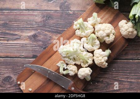 Küchenmesser und Blumenkohl auf Schneidebrett Stockfoto