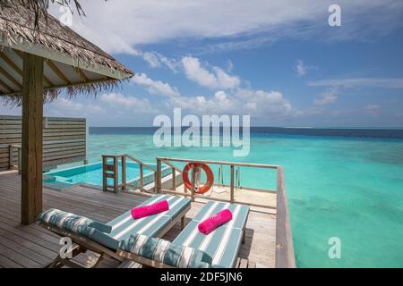 Fantastische Villa über dem Wasser, Blick auf die Terrasse mit Sonnenliegen unter dem Sonnenschirm, Luxus-Pool-Hotel mit herrlichem Meerblick. Schönes Spa oder Wellness Stockfoto