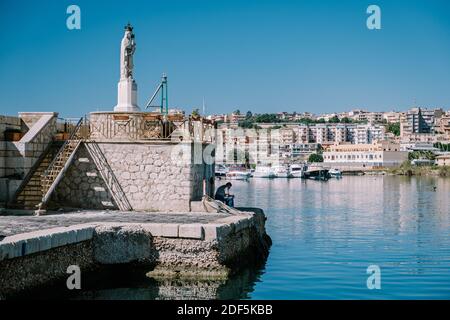 Sciacca Sizilien Oktober 2020, Fischerboote und Menschen reparieren Netze in der bunten Stadt Sciacca mit Blick auf ihren Hafen. Provinz Agrigento, Sizilien. Hochwertige Fotos Stockfoto