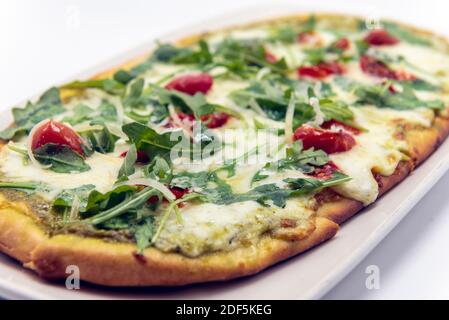 Blick von oben auf ovale arugula Pesto Fladenbrot Mahlzeit mit geschmolzenem Käse und Rucola auf der Oberseite. Stockfoto