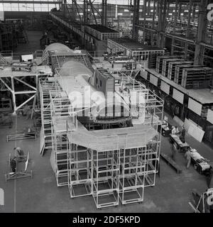 1950er Jahre, historische Ansicht von oben, die das Innere eines großen Flugzeughangars zeigt, in dem ein Kommunkerflugzeug gebaut wird, England, Großbritannien. Stockfoto