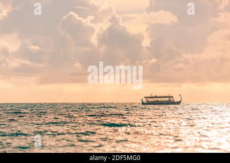 Maldives Sunset Cruise mit Dhoni Boot auf den Malediven Inseln. Tropischer Sonnenuntergang, Meereslandschaft. Menschen, die den Sonnenuntergang genießen und Meeresleben suchen Stockfoto