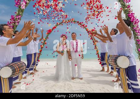 10.08.19 Inseln der Malediven. Junge asiatische paar küssen bei Hochzeitsempfang unter Blumen. Liebe Romantik Hochzeitszeremonie weißen Sandstrand in der Nähe des Meeres Stockfoto