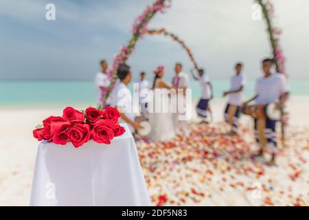 10.08.19 Inseln der Malediven. Junge asiatische paar küssen bei Hochzeitsempfang unter Blumen. Liebe Romantik Hochzeitszeremonie weißen Sandstrand in der Nähe des Meeres Stockfoto