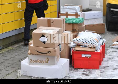 München, Deutschland. Dezember 2020. Paketvolumen und Online-Handel boomen in Zeiten der Corona-Virus-Pandemie. DHL Paketzusteller, Paketdienstleister, bei der Arbeit legt Paket in ein Fach einer Packstation. Entlädt seine Paket Auto, Postbus, DHL, Paket, Pakete, Paketdienst, liefern, liefern, entladen, Versand, Transporter, Handfahrzeug. Quelle: dpa/Alamy Live News Stockfoto
