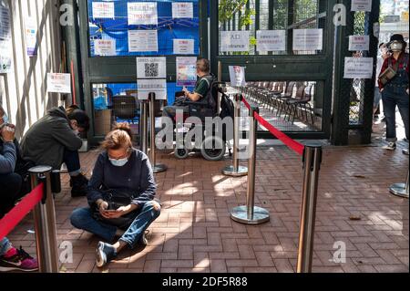 Ein Besucher, der eine Maske trägt, wird auf seinem Telefon gesehen, während er wartet, um auf Coronavirus (COVID-19) in einem Community Testing Center in Hongkong getestet zu werden. Tage nach dem raschen Anstieg der positiven COVID-19-Fälle hat die Regierung Hongkongs Testzentren eingerichtet, in denen die Menschen auf COVID-19 getestet werden können und das Ergebnis innerhalb von 24 Stunden erhalten. Stockfoto