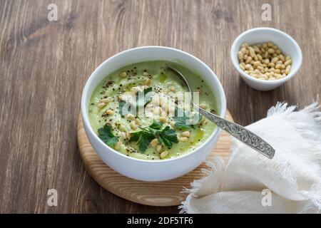 Blumenkohlpüree mit Petersilie und Pinienkernen in einer weißen Schüssel auf einem Holztisch. Köstliche Diät-Essen Stockfoto