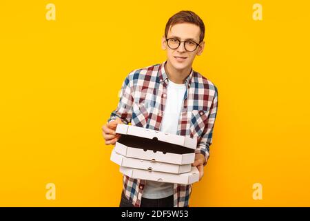 Mann mit einer Schachtel Pizza auf gelbem Hintergrund, ein glücklicher Mann mit einer Pizza in den Händen Stockfoto