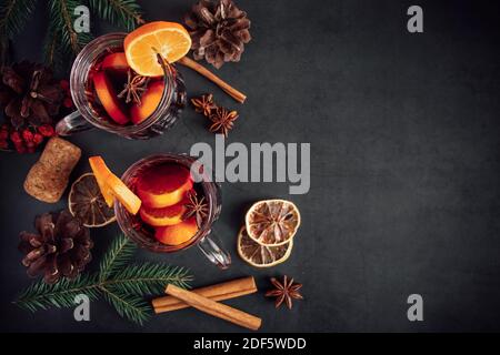 Zwei Gläser Glühwein mit Früchten und Gewürzen auf dunklem Hintergrund. Winter wärmende Urlaubsgetränk. Stockfoto