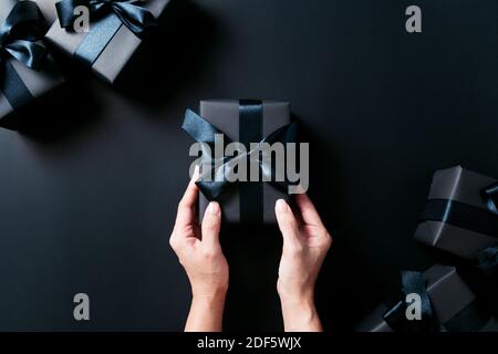 Boxing Day Sale Konzept, Frau Hand geben die Geschenkbox auf schwarzem Hintergrund Stockfoto
