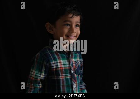 Portrait of Indian niedlichen kleinen fröhlichen Brünette Tamil Baby junge tragen lässige Kleid in stilvoller Stimmung in einem schwarzen Hintergrund. Stockfoto