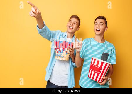 Bild von zwei aufgeregt schönen Teenagern, Jungs beobachten einen interessanten Film und essen Popcorn Stockfoto