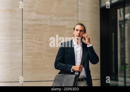 Geschäftsmann mit Umhängetasche im Freien auf dem Handy reden Stockfoto