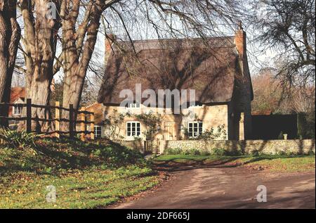 Traditionelles, aus Stein gebautes, reetgedeckten English Village Cottage mit strahlendem Sonnenschein Auf der Spur Stockfoto