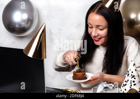 Frau zündet Kerze auf festlichem Cupcake an und macht ein Video Anruf feiert Geburtstag online während Quarantäne, weil Pandemie COVID-19 Stockfoto