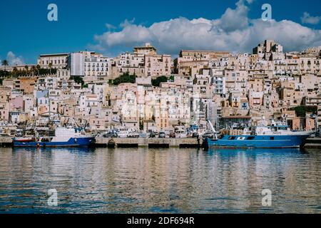 Sciacca Sizilien Oktober 2020, Fischerboote und Menschen reparieren Netze in der bunten Stadt Sciacca mit Blick auf ihren Hafen. Provinz Agrigento, Sizilien. Hochwertige Fotos Stockfoto