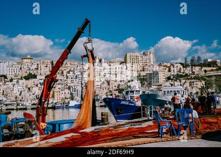 Sciacca Sizilien Oktober 2020, Fischerboote und Menschen reparieren Netze in der bunten Stadt Sciacca mit Blick auf ihren Hafen. Provinz Agrigento, Sizilien. Hochwertige Fotos Stockfoto