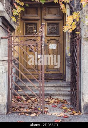 Der Eingang zu einem alten Haus mit einem rostigen Tor und einer abgenutzten Tür. Stockfoto