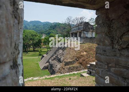 Blick durch das Tor zu einer kleinen Pyramide Maya Ruine Tempel an der archäologischen Stätte von Palenque umgeben von grünen tropischen Bäumen, Chiapas, Mexiko Stockfoto