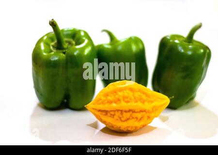 Gelbe bittere Kürbis zwischen grünen Paprika mit isoliertem Hintergrund, ungerade heraus Stockfoto