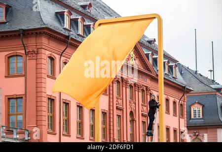 Mainz, Deutschland. Dezember 2020. Ein Mitarbeiter der Firma, die das Kunstwerk "drei Farben" gebaut hat, steht auf einer Leiter an einer der drei Flaggen. Vor der Baustelle des landtags wurde ein Testlauf durchgeführt, um die tatsächliche Wirkung des Kunstwerks zu beurteilen. Der Entwurf eines Berliner Künstlers mit dem Titel "drei Farben" wurde mit großer Mehrheit zum Gewinner des Wettbewerbs "Kunst am Bauen" gewählt. Das Kunstwerk basiert auf dem Hambacher Festival. Quelle: Andreas Arnold/dpa/Alamy Live News Stockfoto