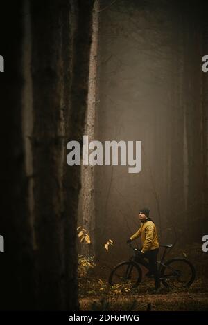 Schöner junger Mann, der beim Radfahren durch den Herbst eine Bremse zieht Wald Stockfoto