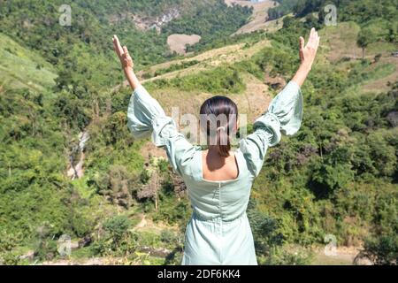Das Bild hinter den Frauen heben ihre Arme blickte auf die Berge und Bäume. Stockfoto