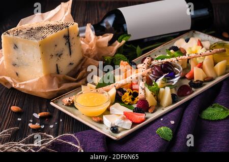 Käseplatte mit Trauben und Nüssen serviert. Verschiedene Käsesorten Camembert, Brie, Parmesan Blauschimmelkäse, Ziege mit Trauben, Gressini-Sticks, Cashews, Honig und Stockfoto