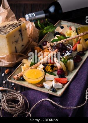 Käseplatte mit Trauben und Nüssen serviert. Verschiedene Käsesorten Camembert, Brie, Parmesan Blauschimmelkäse, Ziege mit Trauben, Gressini-Sticks, Cashews, Honig und Stockfoto