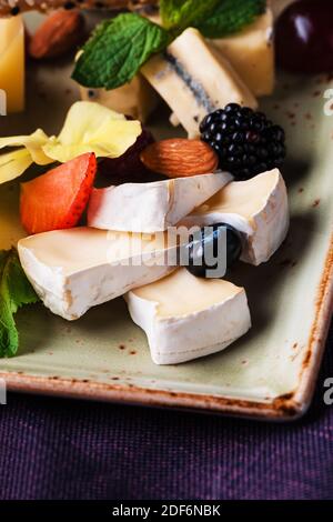 Käseplatte mit Trauben und Nüssen serviert. Verschiedene Käsesorten Camembert, Brie, Parmesan Blauschimmelkäse, Ziege mit Trauben, Gressini-Sticks, Cashews, Honig und Stockfoto