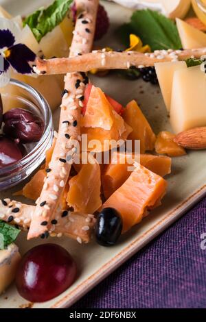 Käseplatte mit Trauben und Nüssen serviert. Verschiedene Käsesorten Camembert, Brie, Parmesan Blauschimmelkäse, Ziege mit Trauben, Gressini-Sticks, Cashews, Honig und Stockfoto