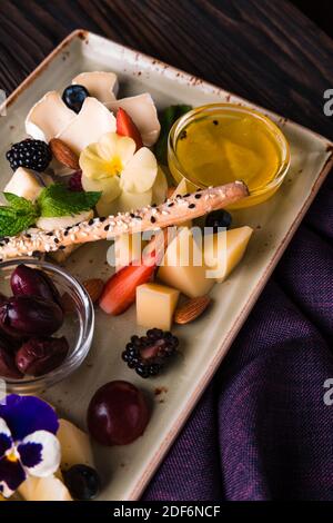 Käseplatte mit Trauben und Nüssen serviert. Verschiedene Käsesorten Camembert, Brie, Parmesan Blauschimmelkäse, Ziege mit Trauben, Gressini-Sticks, Cashews, Honig und Stockfoto