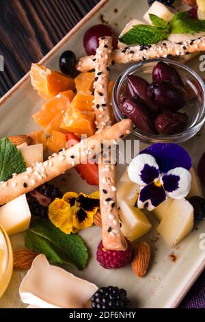 Käseplatte mit Trauben und Nüssen serviert. Verschiedene Käsesorten Camembert, Brie, Parmesan Blauschimmelkäse, Ziege mit Trauben, Gressini-Sticks, Cashews, Honig und Stockfoto