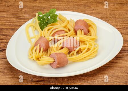 Kinder Pasta Spaghetti mit Würstchen und Basilikum Stockfoto