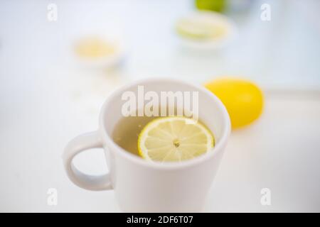 Tasse Zitronentee auf einem Tisch mit Limetten und Zitronen Stockfoto